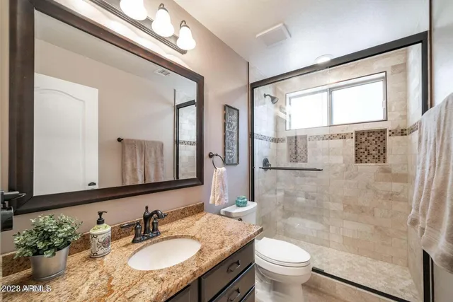 a bathroom with a granite countertop sink toilet a mirror and shower