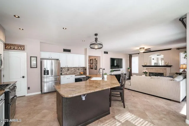 a living room with stainless steel appliances furniture a fireplace and a open kitchen