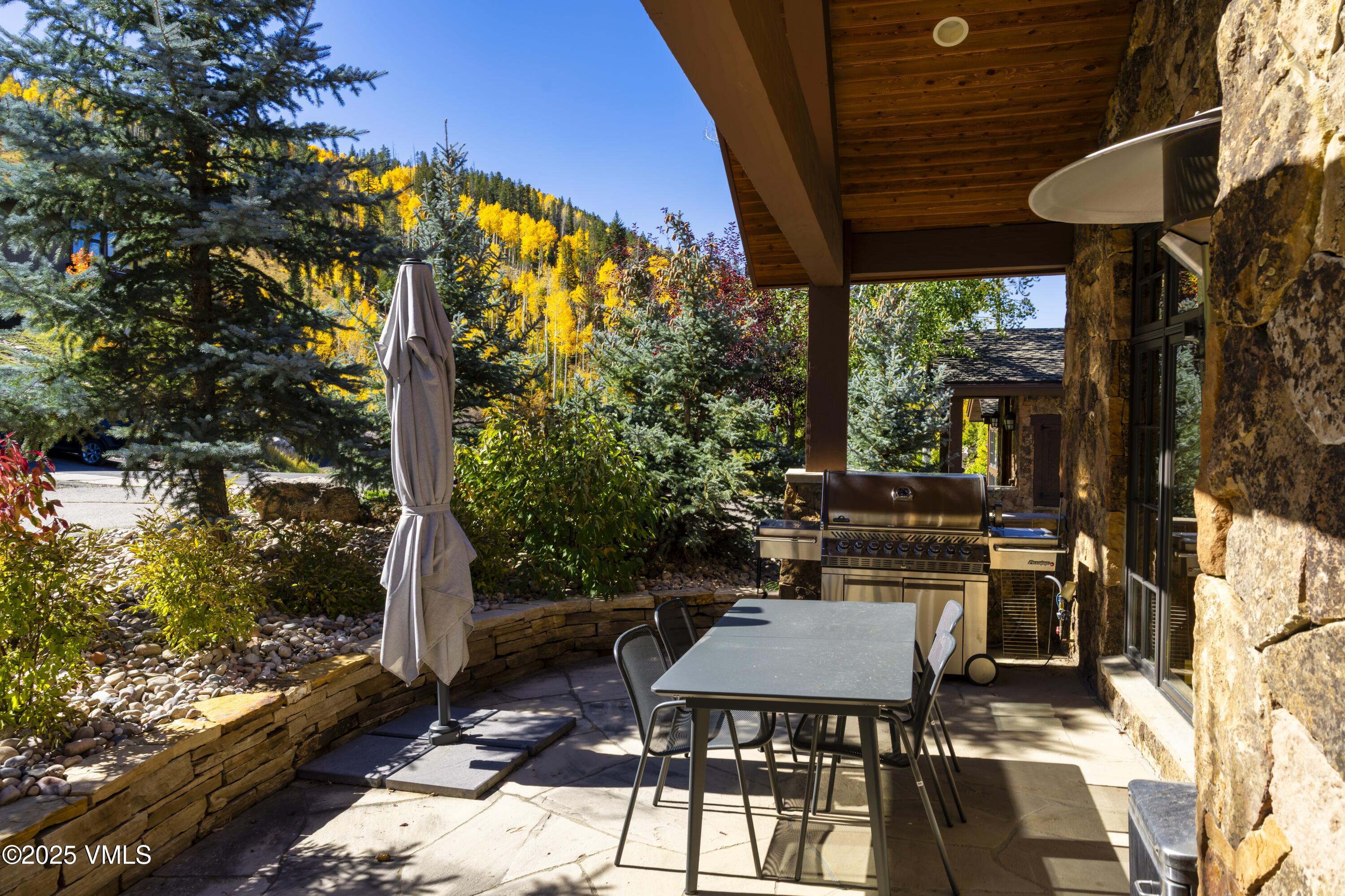 2735 Snowberry Drive, Unit B Vail, CO 81657 - Photo 40 of 48 a view of a patio with table and chairs under an umbrella with a small yard