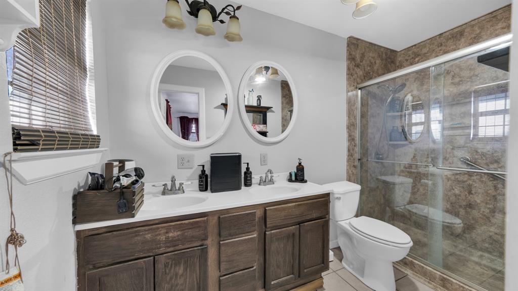 11500 Bowden Road Lipan, TX 76462 - Photo 24 of 32 Bathroom with a shower with shower door, double vanity, tile patterned floors, and toilet