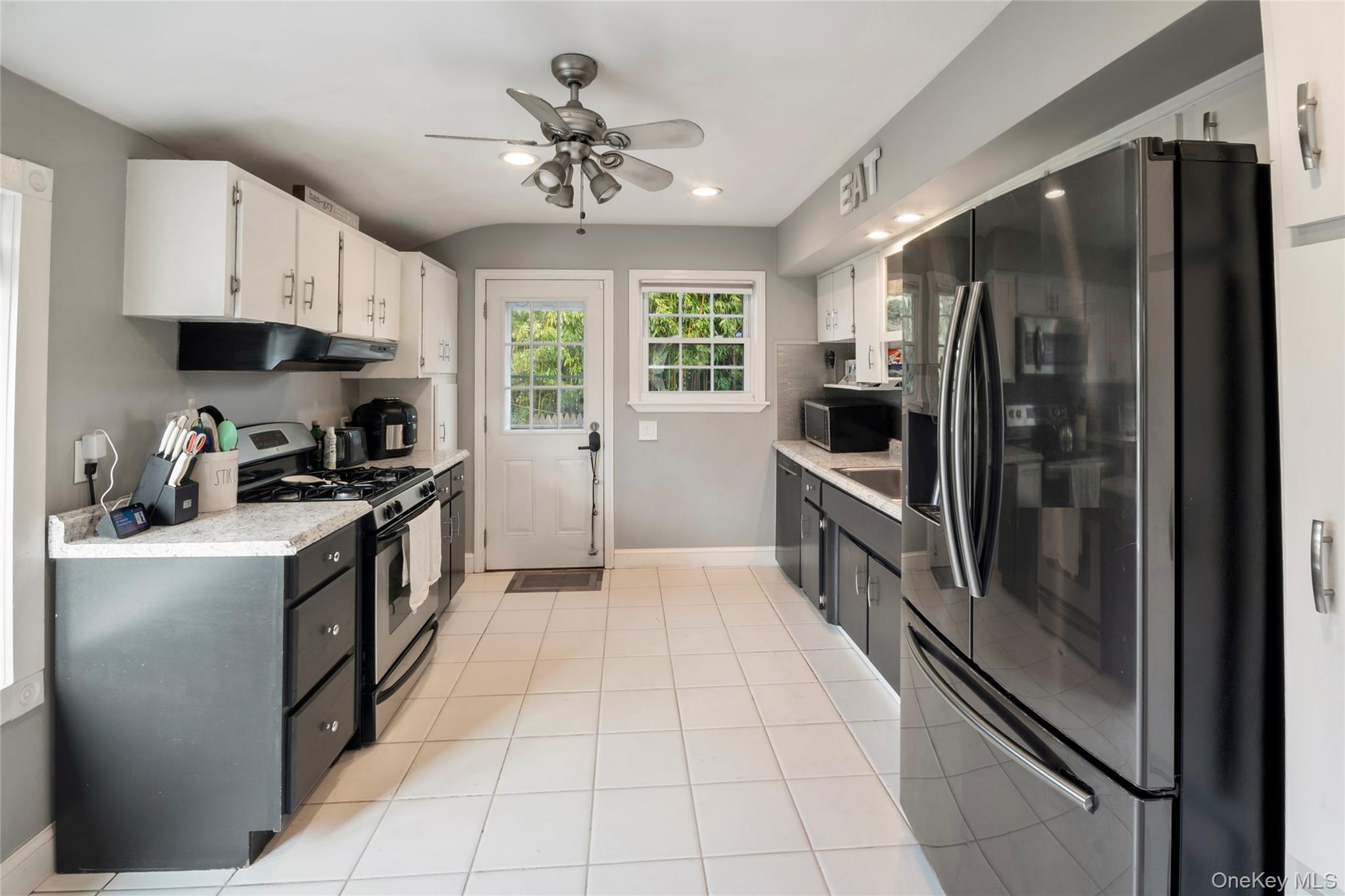 277 Horseblock Road Farmingville, NY 11738 - Photo 3 of 28 Kitchen featuring appliances with stainless steel finishes, white cabinets, a ceiling fan, light tile patterned floors, and under cabinet range hood
