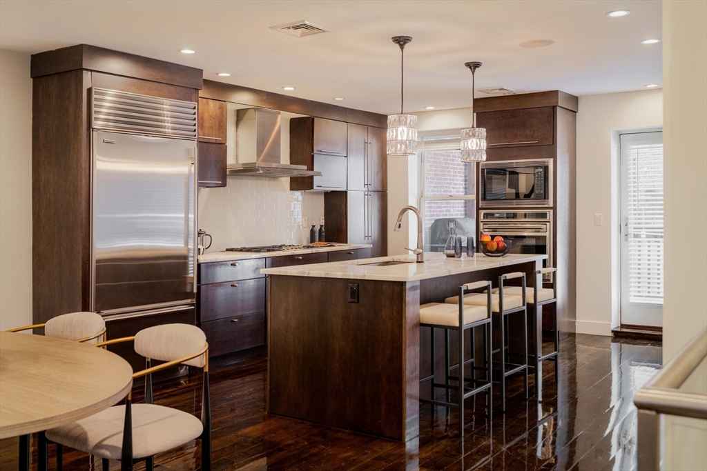 92 Waltham Street, Unit 1A Boston, MA 02118 - Photo 4 of 41 a kitchen with stainless steel appliances granite countertop a stove refrigerator and chairs