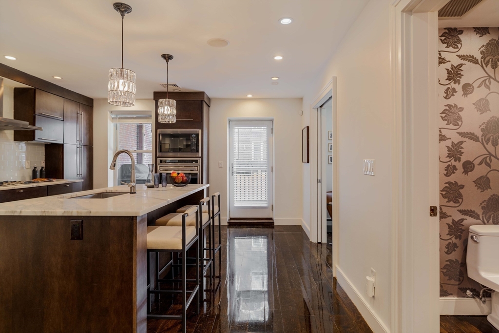 92 Waltham Street, Unit 1A Boston, MA 02118 - Photo 8 of 41 a kitchen with stainless steel appliances granite countertop a refrigerator a stove and a sink with wooden floor
