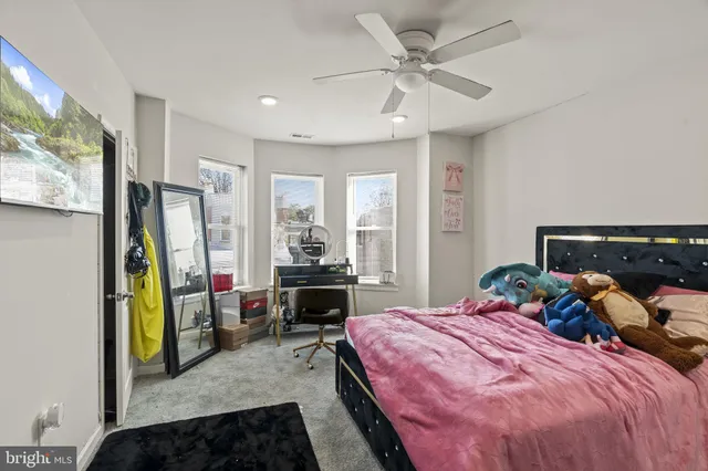 a bedroom with a bed a large window with table and chair