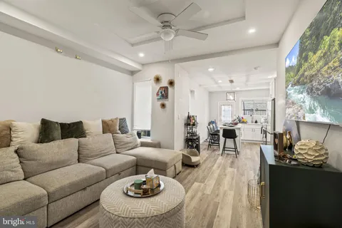 a living room with furniture kitchen view and a large window