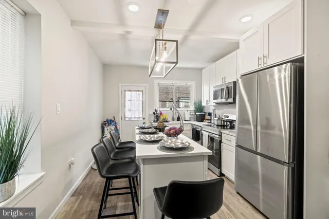 a kitchen with a refrigerator a sink dishwasher a dining table and chairs with wooden floor