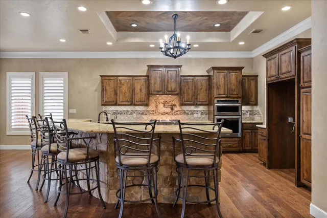 a kitchen with stainless steel appliances kitchen island granite countertop a refrigerator a stove a microwave oven a dining table and chairs with wooden floor