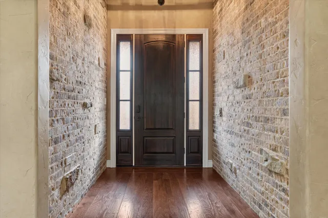 a view of a hallway with wooden floor and brick walls