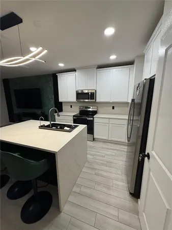 a kitchen with stainless steel appliances a refrigerator a sink a stove a microwave oven a sink with island and chairs