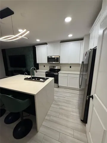 a kitchen with stainless steel appliances a refrigerator a sink a stove a microwave oven a sink with island and chairs