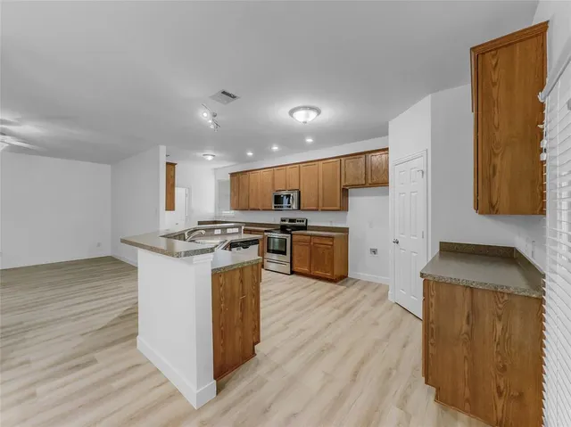 a view of a kitchen with kitchen island wooden floor and stainless steel appliances