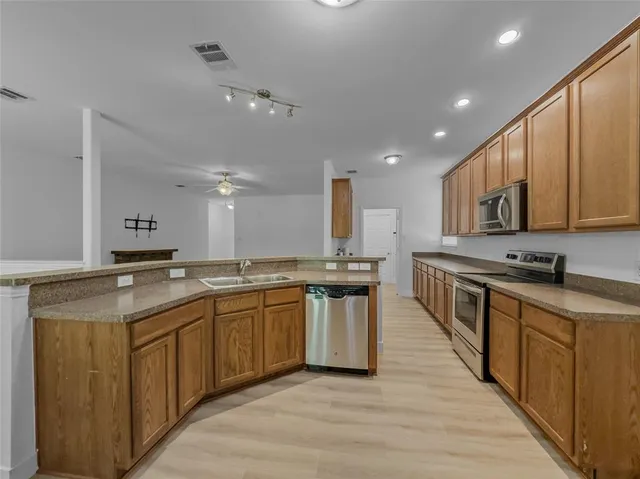 a large kitchen with stainless steel appliances granite countertop a sink counter space and wooden floor