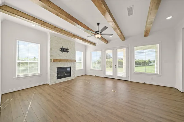 a view of an empty room with wooden floor fireplace and a window