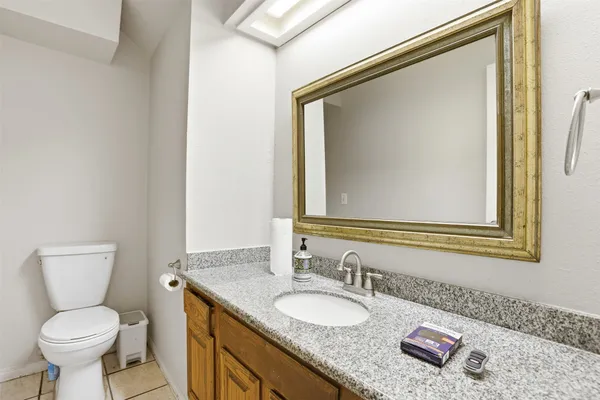 a bathroom with a granite countertop toilet sink and mirror