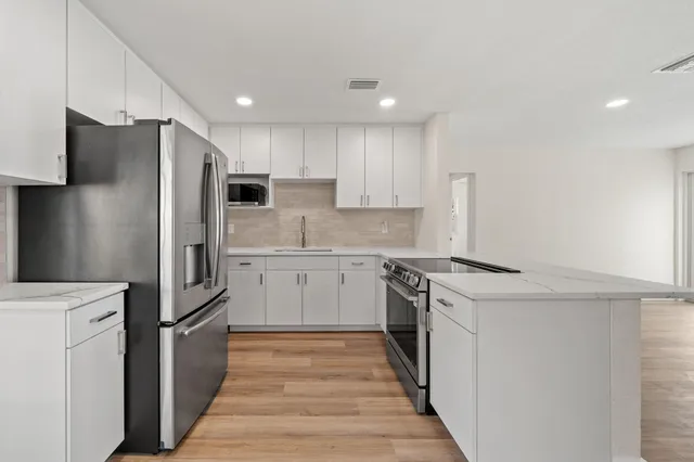 a kitchen with a refrigerator stove and white cabinets