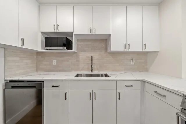 a kitchen with white cabinets and sink