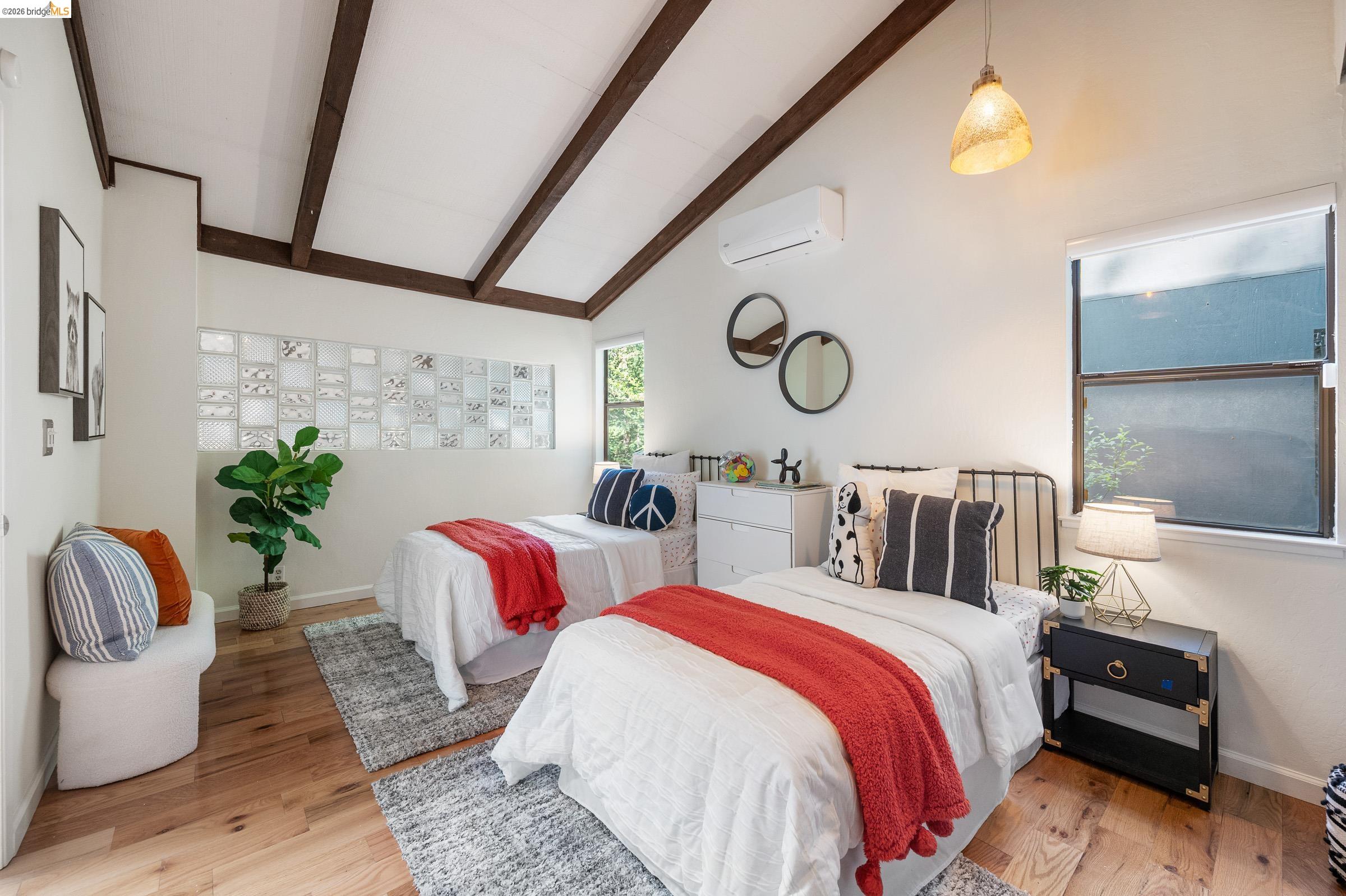 6600 Heather Ridge Way Oakland, CA 94611 - Photo 32 of 66 Vaulted ceilings with exposed wood beams, wood-finish flooring, glass block wall feature, multiple windows, and a wall-mounted climate control unit