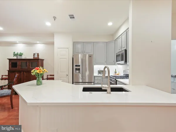 a kitchen with stainless steel appliances kitchen island granite countertop a refrigerator a stove a sink a dining table and chairs with wooden floor