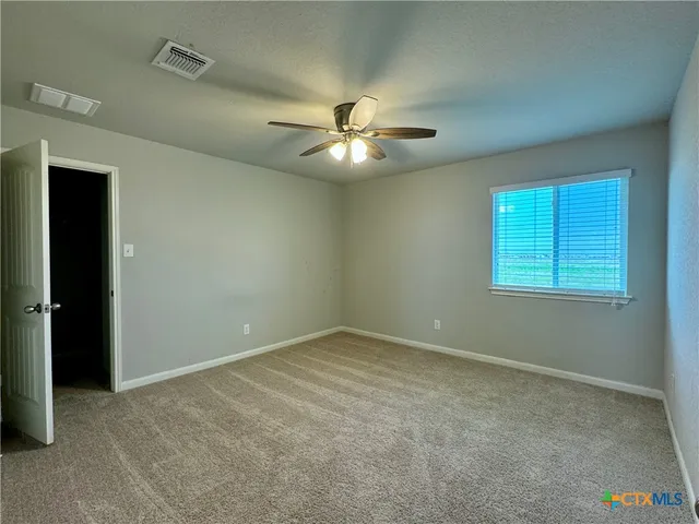 an empty room with windows and fan