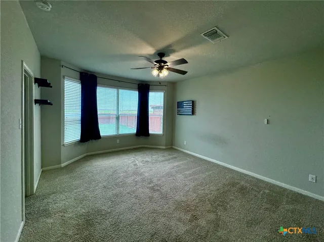 an empty room with windows and fan