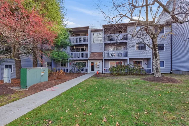 a view of a big yard in front of a brick house with a large tree