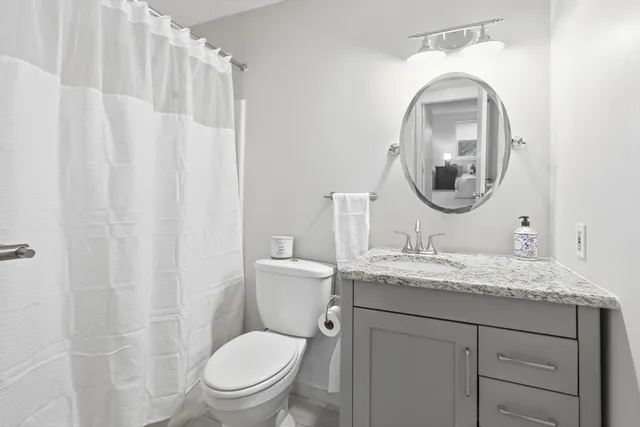 a bathroom with a granite countertop toilet a sink and a mirror