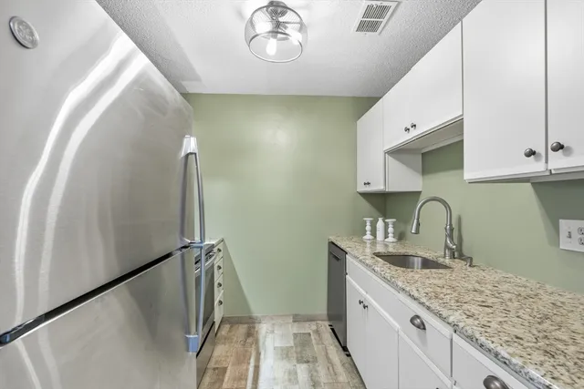 a kitchen with a sink a refrigerator and cabinets