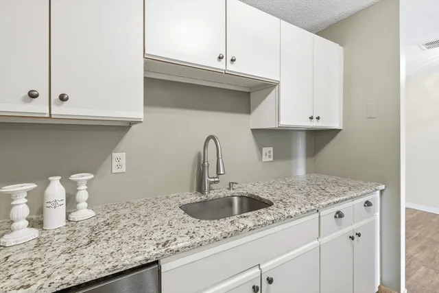 a kitchen with granite countertop white cabinets and a sink