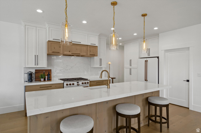 3349 Oxford Loop Morgan, UT 84050 - Photo 4 of 47 Kitchen with light wood-style flooring, dual tone cabinets, a large island, and hanging light fixtures