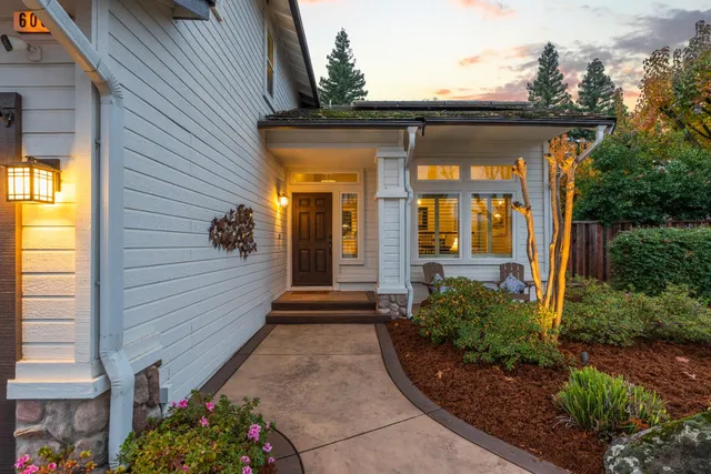 a front view of a house with a garden and trees