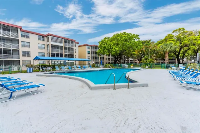 a view of a swimming pool with a lounge chairs in front of a house