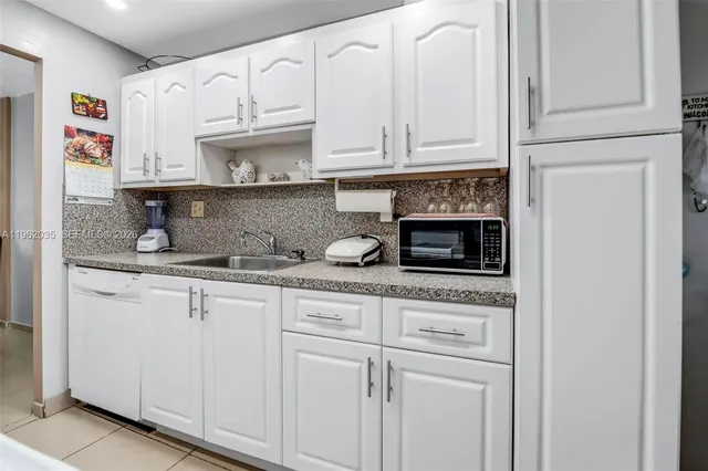 a kitchen with stainless steel appliances granite countertop white cabinets and a sink