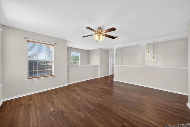 a view of an empty room with a window and wooden floor
