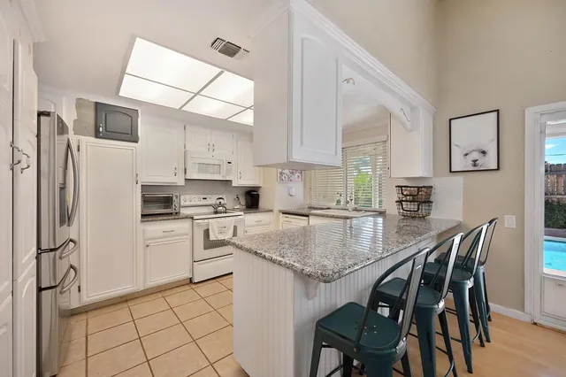 a kitchen with stainless steel appliances granite countertop a stove a sink dishwasher a refrigerator with a dining table and chairs