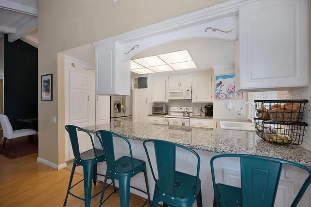 a kitchen with stainless steel appliances granite countertop a stove top oven a sink a refrigerator dining table and chairs