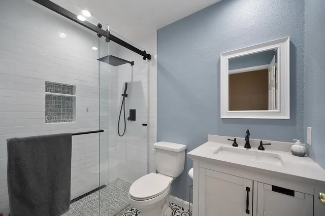 a bathroom with a granite countertop sink toilet a mirror and shower