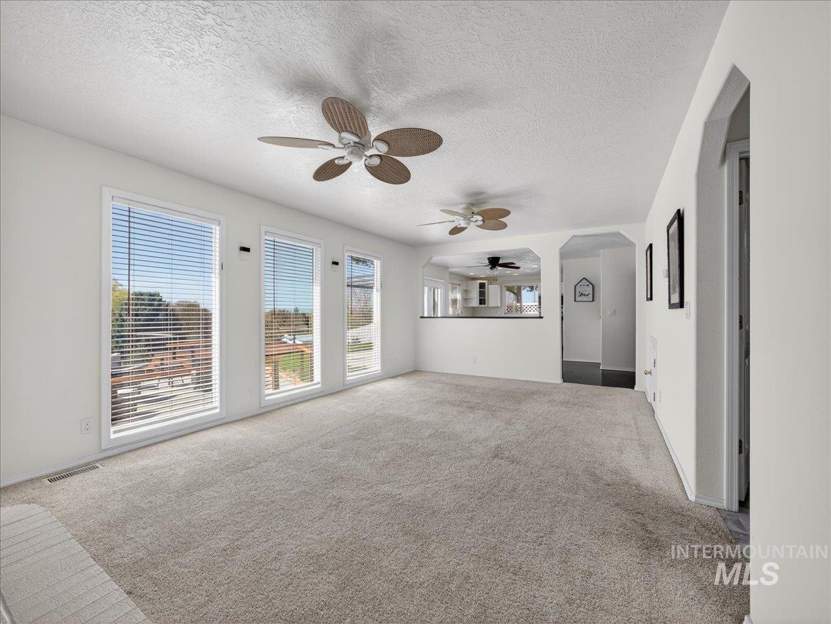 398 Pebble Beach Way Eagle, ID 83616 - Photo 12 of 35 Spacious living area featuring light-toned carpeting and multiple windows with horizontal blinds