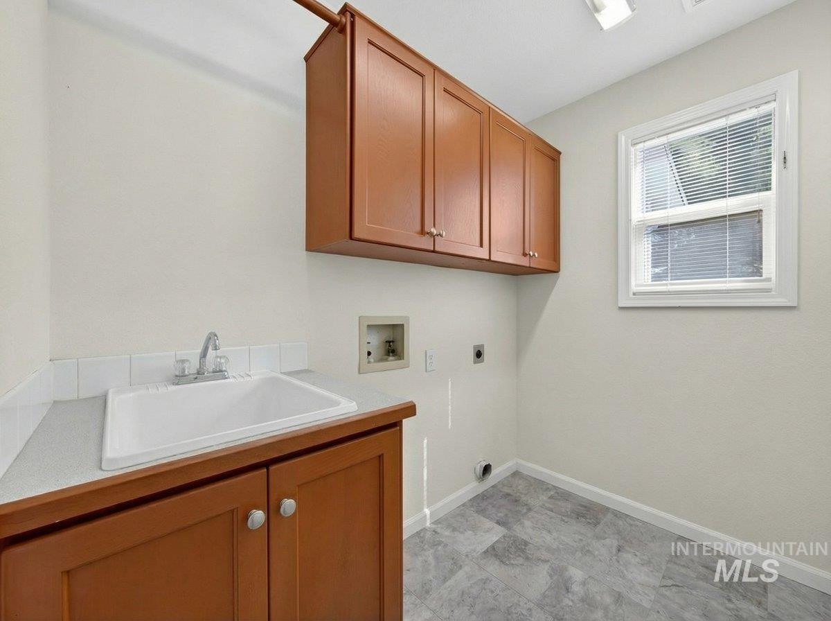 398 Pebble Beach Way Eagle, ID 83616 - Photo 14 of 35 Utility room with a sink, wood cabinetry, and a window