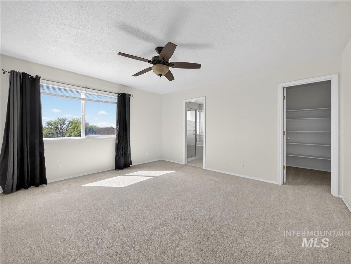 398 Pebble Beach Way Eagle, ID 83616 - Photo 15 of 35 Carpeted room featuring a ceiling fan with integrated lighting, a large window, and light-toned walls