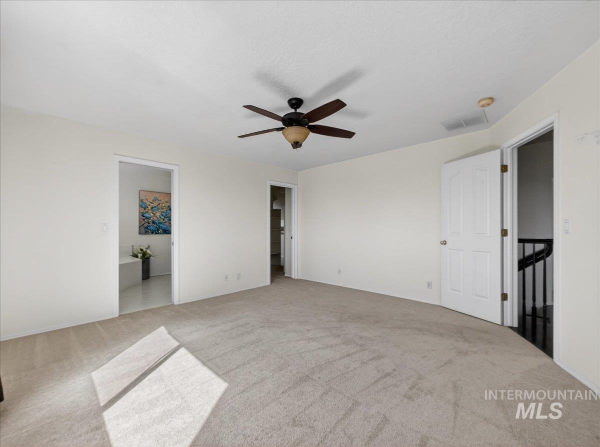 398 Pebble Beach Way Eagle, ID 83616 - Photo 16 of 35 Carpeted interior room featuring a ceiling fan, white walls, and multiple doorways