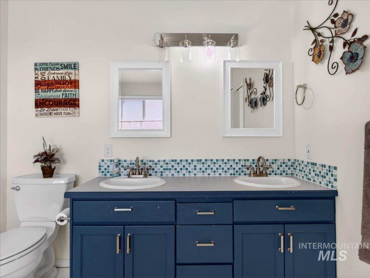398 Pebble Beach Way Eagle, ID 83616 - Photo 19 of 35 Bathroom featuring a dual vanity with a blue painted cabinet, light-colored countertop, and two integrated sinks