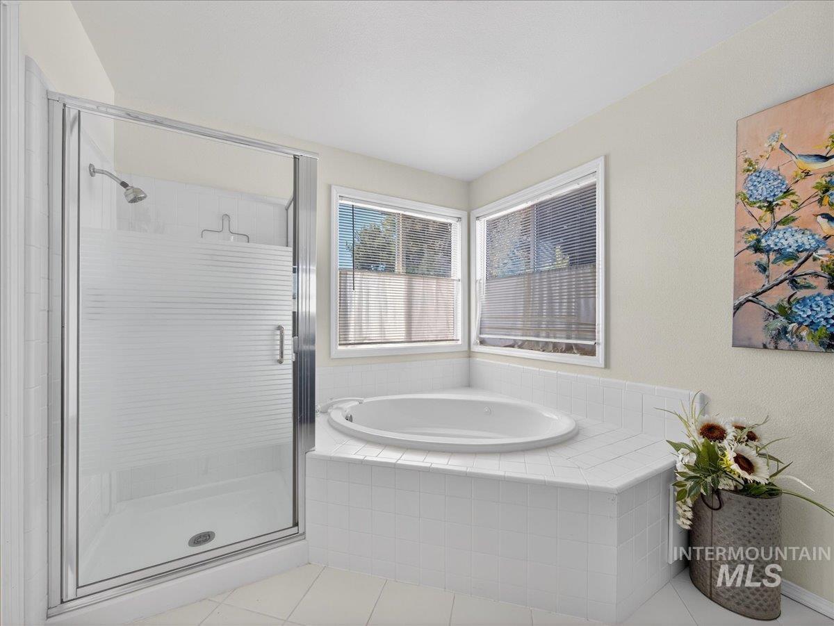 398 Pebble Beach Way Eagle, ID 83616 - Photo 20 of 35 Corner soaking tub with a tiled surround, frosted glass shower enclosure, and two windows with blinds