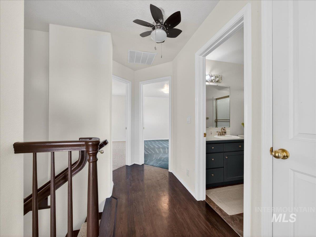 398 Pebble Beach Way Eagle, ID 83616 - Photo 21 of 35 Hardwood-finish flooring extending through the hallway, featuring a dark wood staircase and white risers
