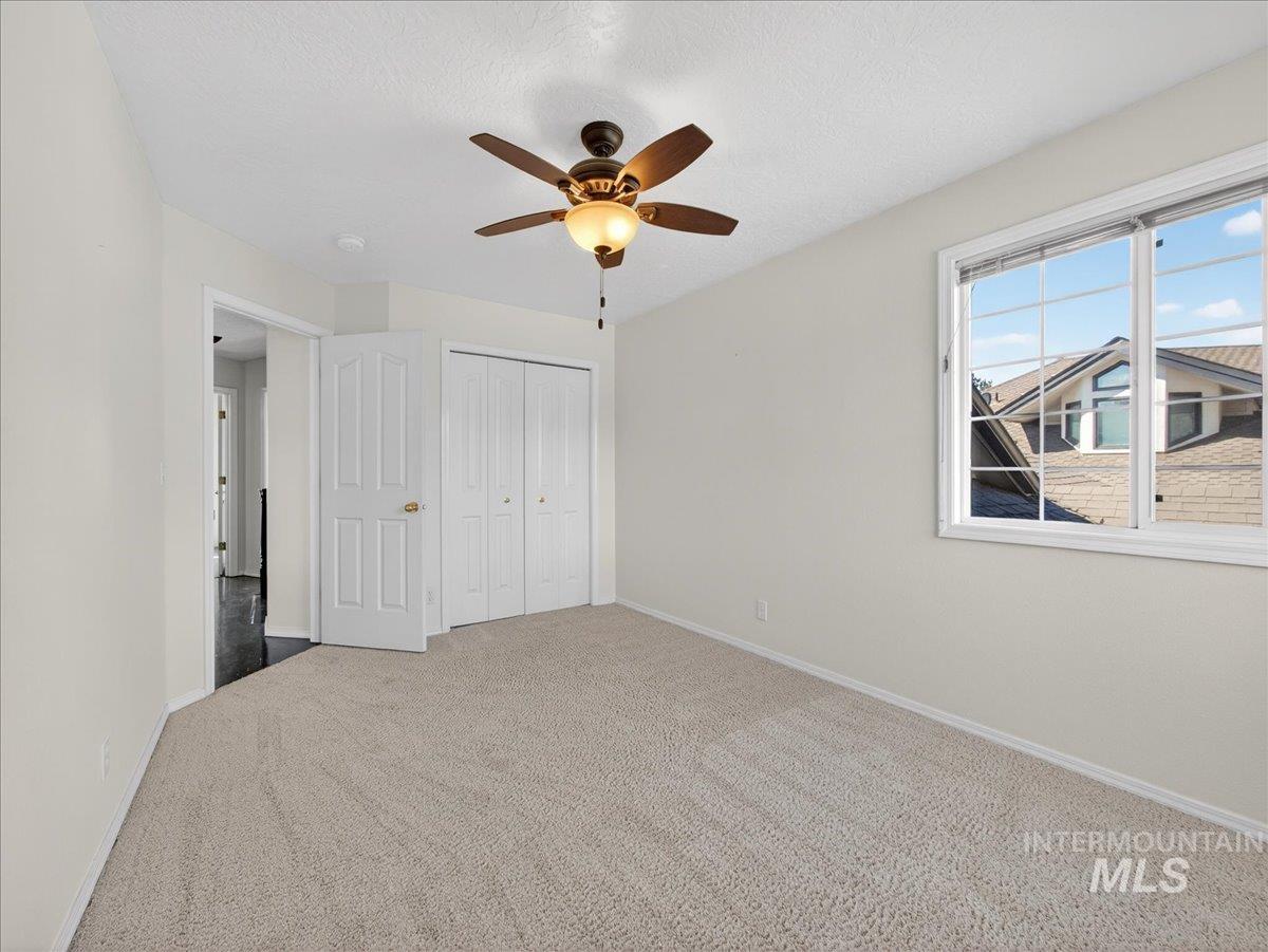 398 Pebble Beach Way Eagle, ID 83616 - Photo 22 of 35 Carpeted room featuring a ceiling fan with integrated lighting, a double-panel window, white baseboards, and bi-fold closet doors