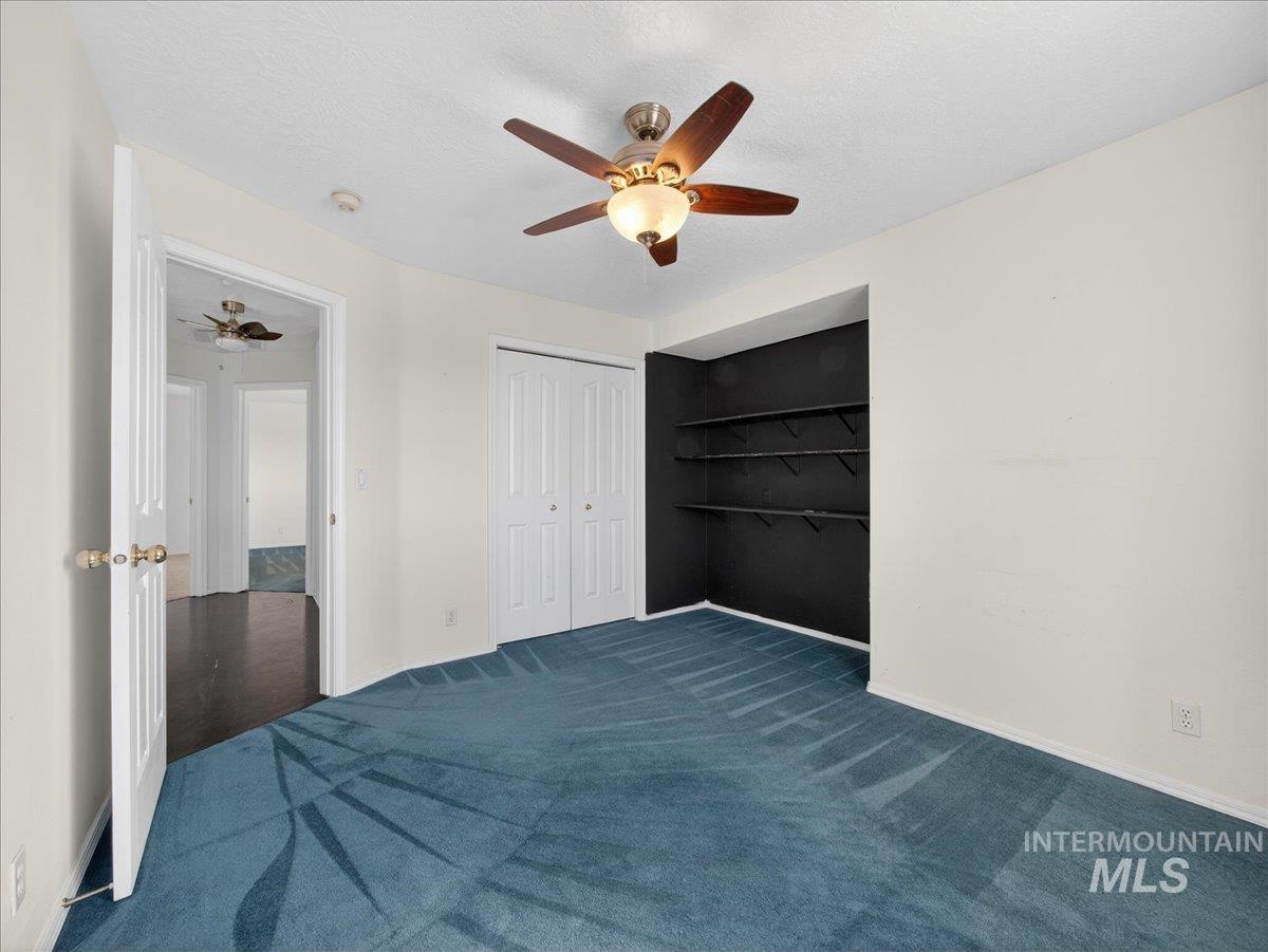 398 Pebble Beach Way Eagle, ID 83616 - Photo 25 of 35 Bedroom featuring patterned blue carpeting, white walls, and a ceiling fan with light fixture