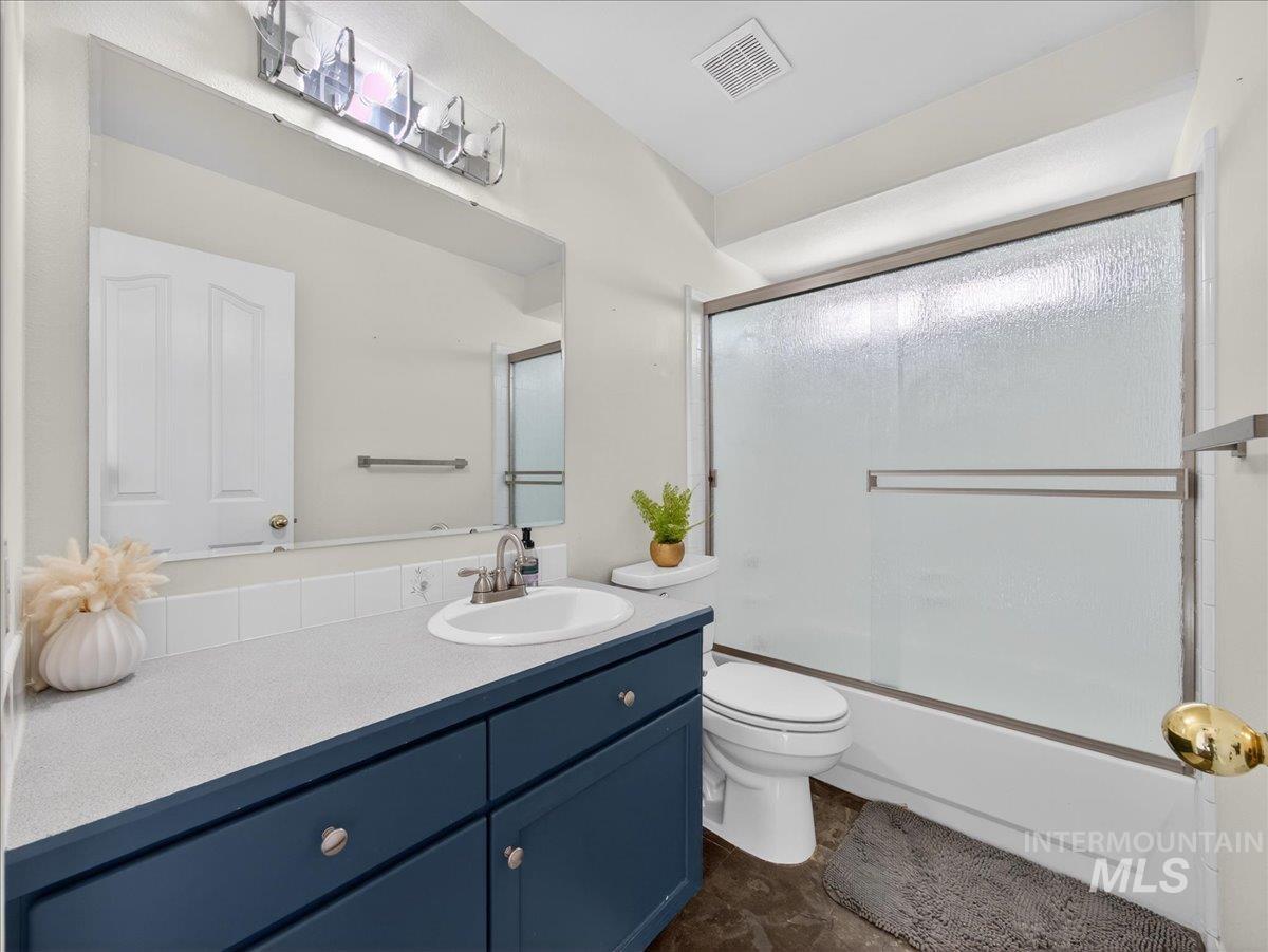 398 Pebble Beach Way Eagle, ID 83616 - Photo 26 of 35 Bathroom featuring a dark blue vanity with silver-toned hardware, a white drop-in sink, and a light-toned countertop
