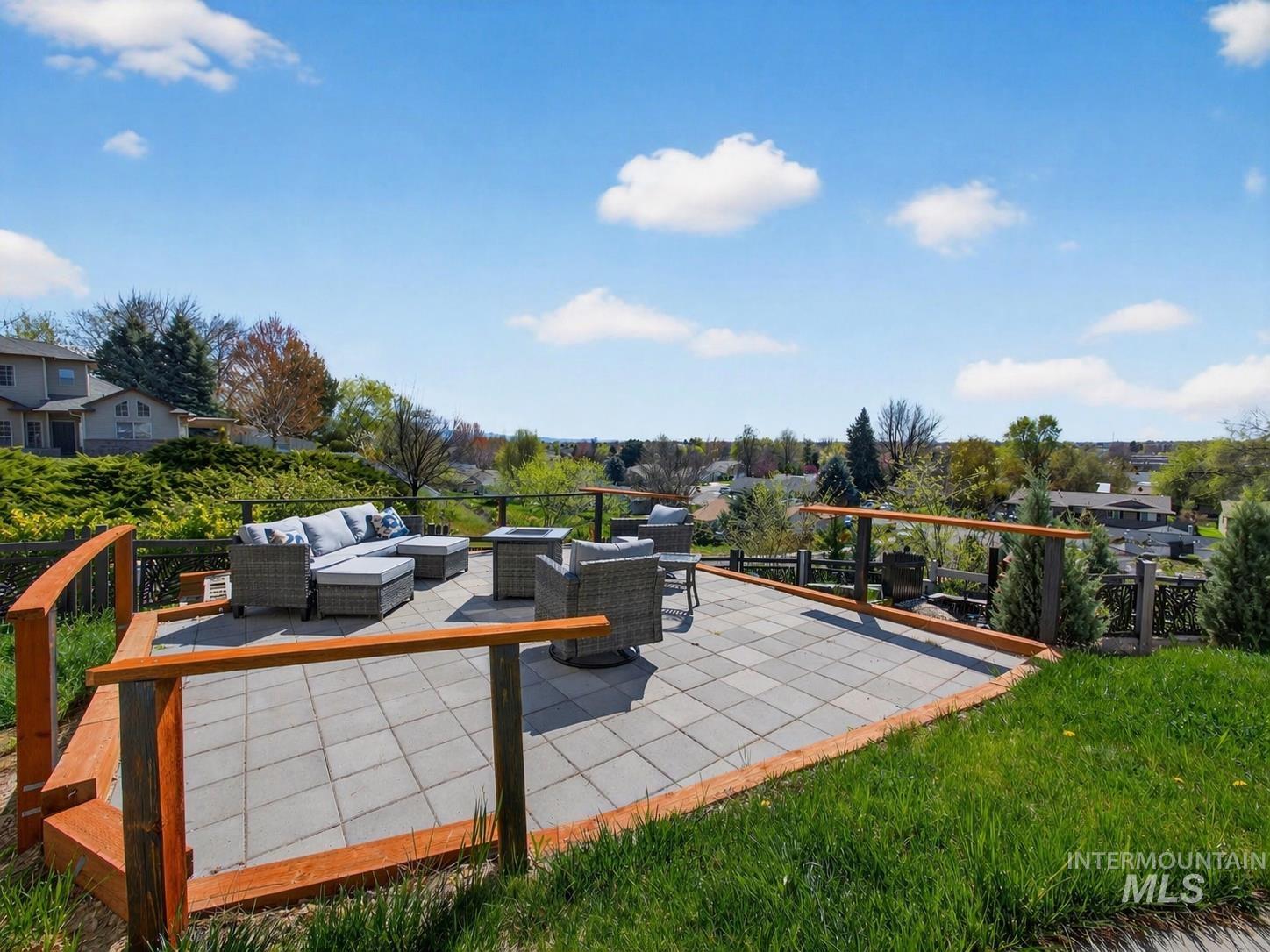 398 Pebble Beach Way Eagle, ID 83616 - Photo 30 of 35 Expansive outdoor patio featuring gray paver stones, a perimeter wood railing, and surrounding green landscaping