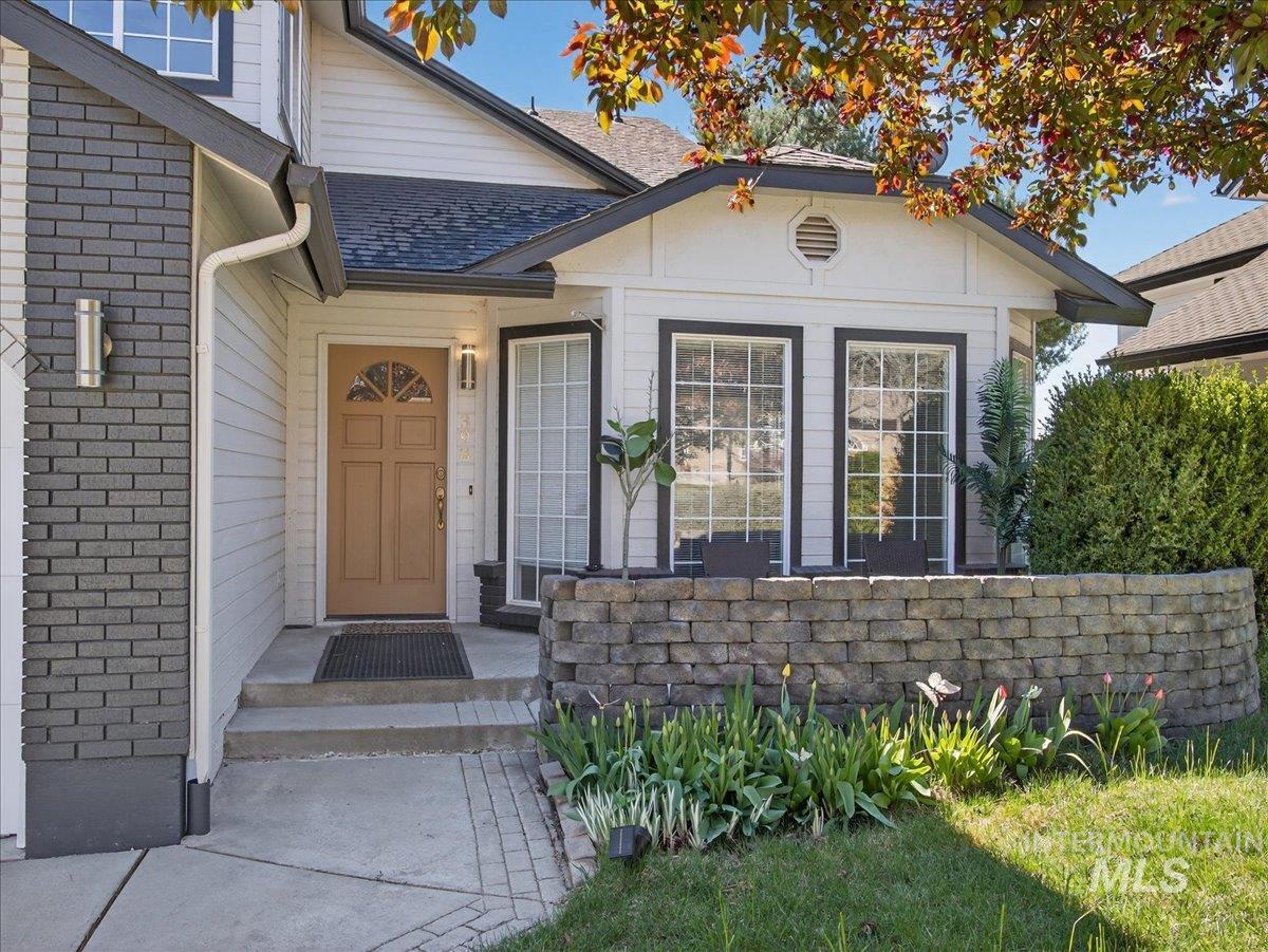 398 Pebble Beach Way Eagle, ID 83616 - Photo 3 of 35 Entryway featuring a wood-panel door with an arched glass insert, flanked by a stacked stone brick facade and siding