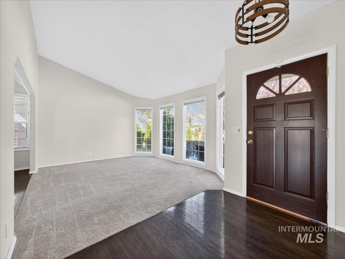 398 Pebble Beach Way Eagle, ID 83616 - Photo 4 of 35 Entryway featuring a dark wood-finish door with an arched transom, a decorative ceiling light fixture, glossy dark wood-finish flooring, and a curved wall of multiple windows