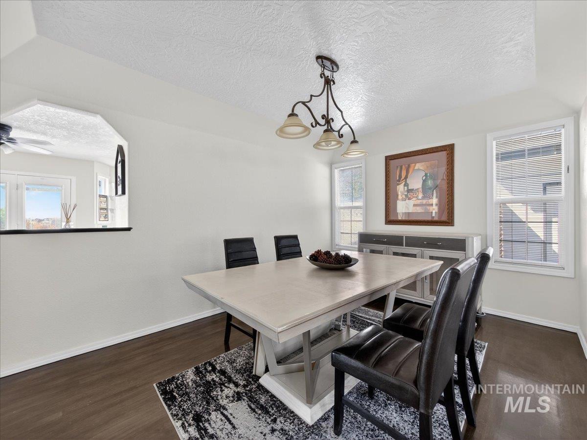 398 Pebble Beach Way Eagle, ID 83616 - Photo 6 of 35 Dining area featuring dark wood-finish flooring, white walls, and a tray ceiling